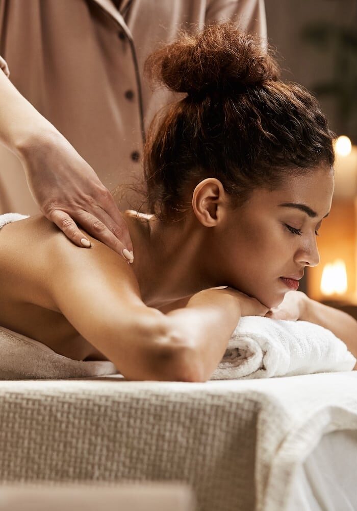 woman-smiling-enjoying-massage-with-closed-eyes-spa-resort
